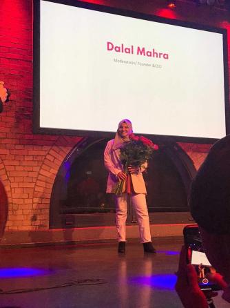 Dalal Mahra - die Gründerin von Kopftuchmädchen - steht auf einer Bühne mit einem Strauß Rosen in der Hand